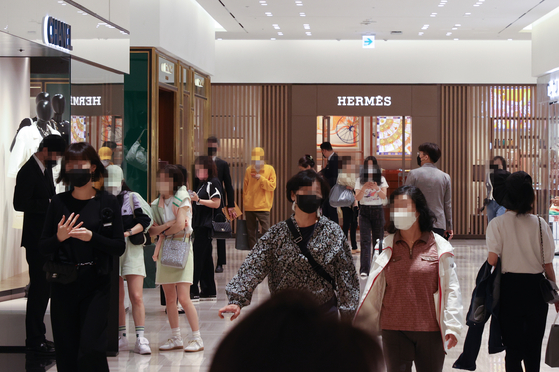 People shop for luxury fashion items at a department store in Seoul in April last year. [YONHAP] 