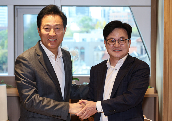 Seoul Mayor Oh Se-hoon, left, and Gimpo Mayor Kim Byung-soo, shake hands ahead of their discussion on the plan to integrate Gimpo into the capital at Seoul City Hall in central Seoul on Monday. [JOINT PRESS CORPS]