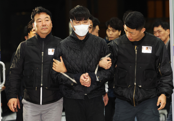 Kim Gil-soo, center, a fugitive who was captured late Monday, is being transported into the Anyang Dongan Police Station in Gyeonggi. [YONHAP] 