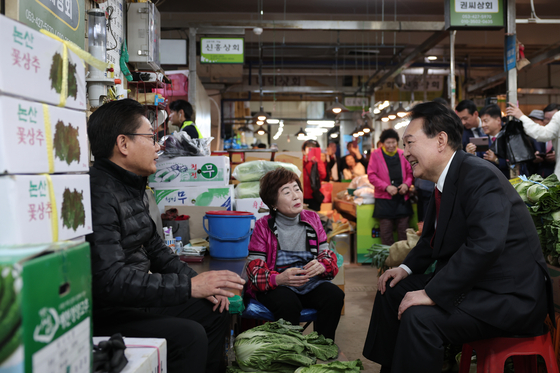President Yoon Suk Yeol, right, chats with local merchants at Chilseong market in Daegu on Tuesday. [PRESIDENTIAL OFFICE]