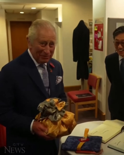 Charles receives a package of kimchi during his visit to the Korean community in New Malden, England, on Wednesday. [CTV NEWS SCREEN CAPTURE]