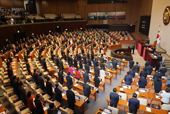 Lawmakers stand during a swearing-in ceremony for People Power Party Rep. Woo Shin-gu at the National Assembly on Thursday. [YONHAP]