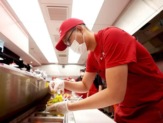 Kim Dong-seon, now vice president at Hanwha Galleria, makes a hamburger at a Five Guys branch in Hong Kong ahead of its opening in Seoul in June. [HANWHA GALLERIA]