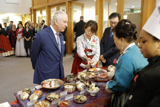 Charles speaks with the Korean Ambassador to Britain Yoon Yeo-cheol and members of the local Korean community to hear about Korea's culture and cuisine in New Malden, England, on Wednesday. [AP]
