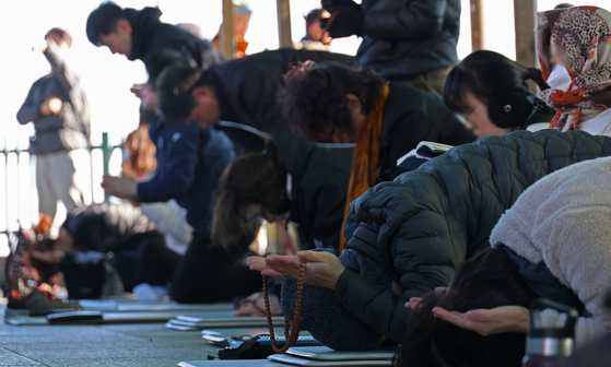 People pray and bow on Mount Palgong in North Gyeongsang on Sunday, for their children who will take the suneung, Korea’s College Scholastic Ability Test, this upcoming Thursday. There will be a total of 504,588 test-takers in this year. [YONHAP] 