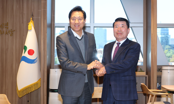 Seoul Mayor Oh Se-hoon, left, and Guri Mayor Baek Kyung-hyeon shake hands at the City Hall in downtown Seoul Monday ahead of their discussion on Guri's incorporation into the capital. [JOINT PRESS CORPS]