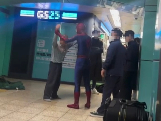 A man in his Spider-Man costume holds arms of the homeless on Saturday at Jamsil Station in southern Seoul. [SCREEN CAPTURE]