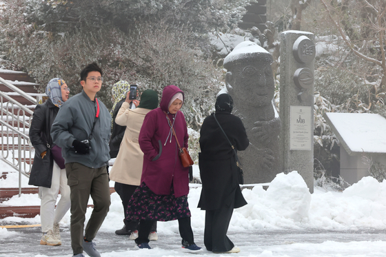 Tourists walk through the snowfall which arrived at Mount Halla in Jeju Island on Monday morning after the heavy snow warning was lifted. Mount Halla experienced a low of minus 5.4 degrees Celsius (22.28 degrees Fahrenheit). [YONHAP]