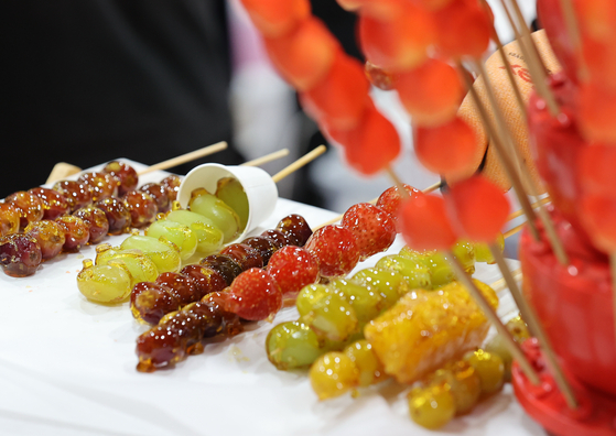 Tanghulu, candied fruits on a stick, are on display at a tanghulu booth in Seoul. [YONHAP]