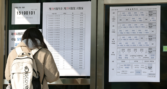 A student taking this year's College Scholastic Ability Test checks her designated test venue at Ewha Girls' High School in Jung District, central Seoul, on Wednesday. [YONHAP] 