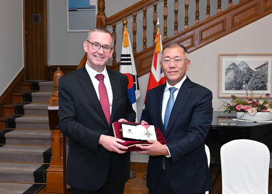 Hyundai Motor Group Chair Euisun Chung, right, receives the Commander of the Most Excellent Order of the British Empire presented by British Ambassador to Korea Colin Crooks on Tuesday at the embassy in central Seoul. [HYUNDAI MOTOR GROUP]