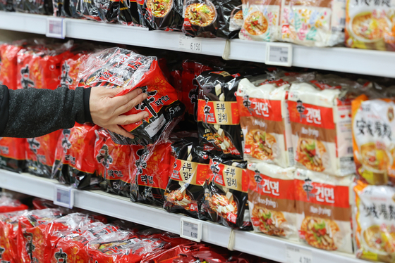A consumer inspects ramyeon products displayed at Nonghyup Hanaro Mart’s branch in Seocho District, southern Seoul, on Wednesday. Food companies’ third quarter earnings were above expectations driven by the global popularity of ramyeon products. Nongshim’s operating profit skyrocketed 103.9 percent on year to 55.7 billion won ($42.7 million) for the July-September period, while Samyang Foods’ operating profit surged 124.7 percent to 43.4 billion won. [YONHAP]
