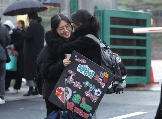Students embrace each other after finishing their college entrance exams in Seoul on Thursday. [YONHAP] 