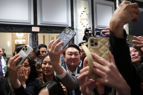 President Yoon Suk Yeol, center, takes selfies with attendees of a meeting with young Korean American scientists and researchers working at a hotel in the San Francisco Wednesday. [JOINT PRESS CORPS]