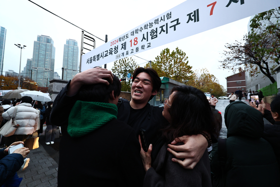 A student hugs his family as he finishes off the college entrance exam in southern Seoul on Thursday. [NEWS1] 
