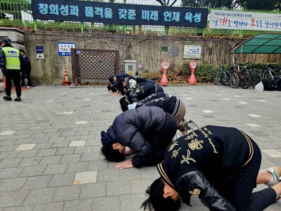 Students bow to seniors taking the College Scholastic Ability Test in Gaepo High School in Gangnam District, southern Seoul, on Thursday morning. [LEE YOUNG-KEUN]