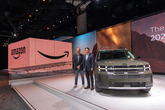 Jose Munoz, right, global chief operating officer of Hyundai Motor, and Marty Mallick, vice president at Amazon, take a photo with the new Santa Fe at the 2023 LA Auto Show in Los Angeles on Thursday. [HYUNDAI MOTOR]