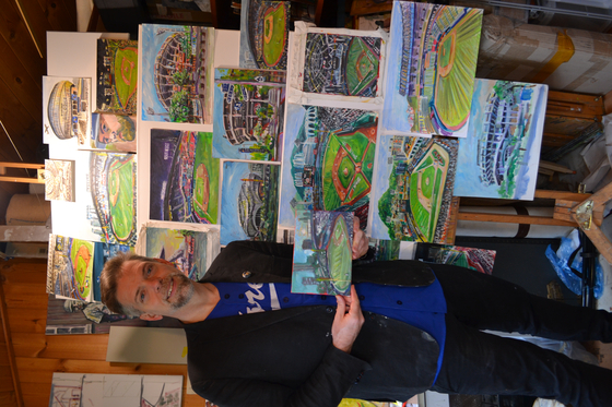 Andy Brown stands next to a collage of his Korean baseball stadium paintings in his studio at his home in England on Nov. 16.  [ANDY BROWN]