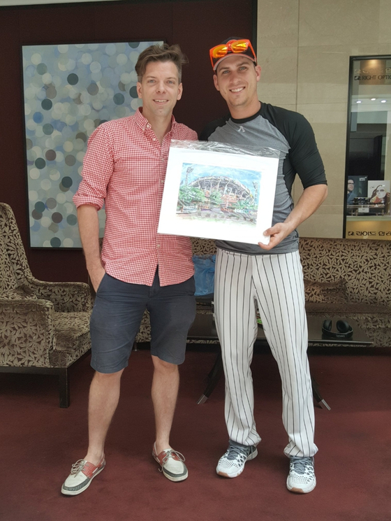 Andy Brown, left, poses with former Lotte Giants infielder Andy Burns and a print of his painting of Sajik Baseball Stadium in Busan. Burns was the first professional baseball player to buy one of Brown' paintings.  [ANDY BROWN]