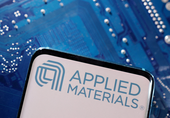 A smartphone with a displayed Applied Materials logo is placed on a computer motherboard in this illustration taken March 6, 2023. [REUTERS]