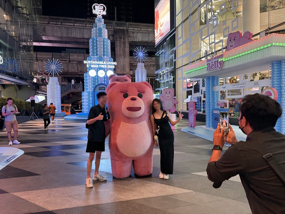 Visitors to Siam Discovery, a major shopping mall in Bangkok, Thailand, pose for a photo with Bellygom, a teddy bear designed by Lotte Home Shopping, on Monday. [YONHAP]