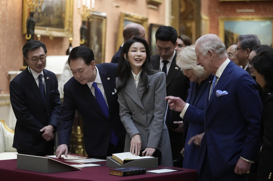 Britain's King Charles, right, with Queen Camilla, shows President Yoon Suk Yeol, left, and first lady Kim Keon Hee, center left, a display of Korean items from the Royal Collection inside Buckingham Palace in London Tuesday. [AP/YONHAP]