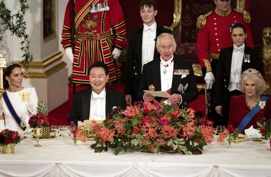 President Yoon Suk Yeol, left, listens to King Charles III speak at the state banquet at Buckingham Palace in London on Tuesday. [AP/YONHAP]