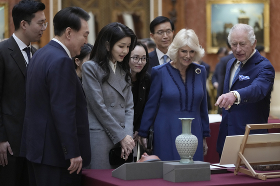 Britain's King Charles, right, with Queen Camilla, shows President Yoon Suk Yeol, left, and first lady Kim Keon Hee a display of Korean items from the Royal Collection inside Buckingham Palace in London Tuesday. [AP/YONHAP]