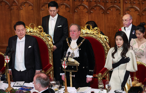 From left, Korean President Yoon Suk Yeol, Lord Mayor of the City of London Michael Mainelli and Korean first lady wife Kim Keon Hee listen to South Korea's national anthem during a banquet at the Guildhall in London Wednesday. [REUTERS/YONHAP]