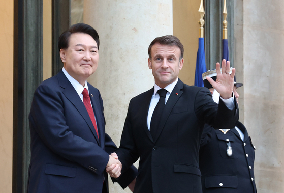 Korean President Yoon Suk Yeol, left, and French President Emmanuel Macron shake hands ahead of a bilateral summit in Paris on Friday. Yoon’s three-day trip to France comes as he is making final efforts to drum up support for hosting the World Expo 2030 in Busan. [JOINT PRESS CORPS]