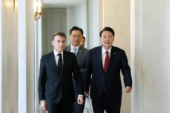 Korean President Yoon Suk Yeol, right, and French President Emmanuel Macron head into a bilateral summit at Elysee Palace in Paris on Friday. [JOINT PRESS CORPS]