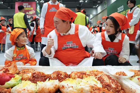President Yoon Suk Yeol, center, gives a thumbs up while tasting kimchi made by a child, left, at a kimjang event calling for national unity through goodwill and sharing at Kintex in Goyang, Gyeonggi, on Monday. First lady Kim Keon Hee seats next to Yoon. [PRESIDENTIAL OFFICE]