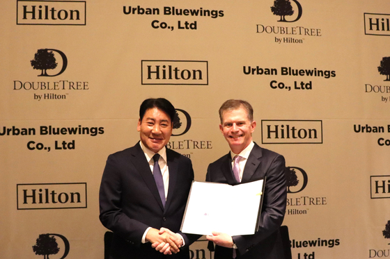 Jun Gu Lee, chairman of Urban Bluewings Co., Ltd., left, and Guy Phillips, senior vice president of development at APAC ex Greater China, Hilton, signed a management agreement on Monday for DoubleTree by Hilton Yeosu. [HILTON]