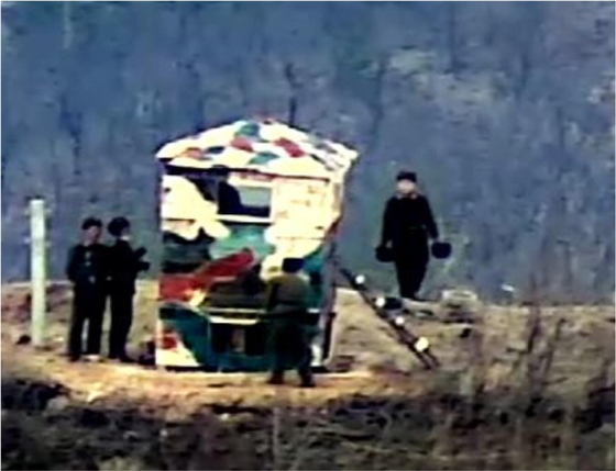 In this photograph released by the South Korean Defense Ministry, North Korean soldiers are seen painting a camouflage pattern on a reconstructed guard post inside the demilitarized zone on Friday, a day after the regime announced it had scrapped an inter-Korean military pact intended to reduce the risk of accidental border clashes. [MINISTRY OF NATIONAL DEFENSE]