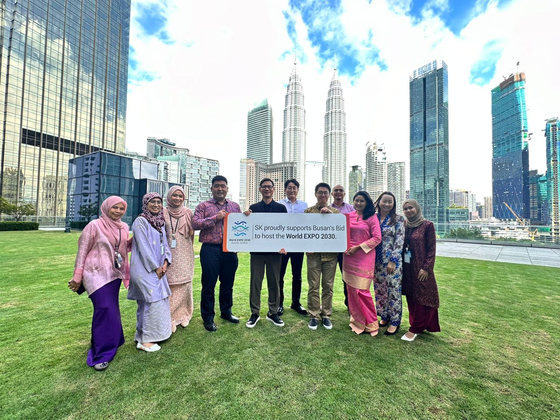 Employees of SK Earthon's Kuala Lumpur branch in Malaysia pose for a photo while holding up a slogan to support Busan's bid to host World Expo 2030. [SK INNOVATION]