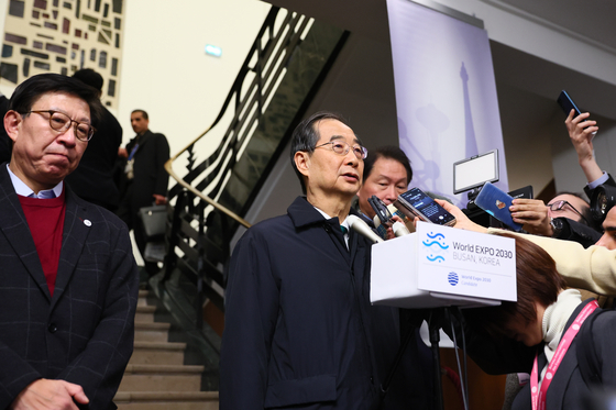 Korean Prime Minister Han Duck-soo, center, speaks to reporters Tuesday after Busan was defeated by Saudi Arabia’s Riyadh in its bid to host the 2030 World Expo at the 173rd general assembly of the Bureau International des Expositions in Paris, accompanied by Busan Mayor Park Park Heong-joon, left. [PRIME MINISTER'S SECRETARIAT]