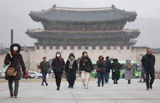 People walk at Gwanghwamun Square in central Seoul as snow falls in the city on Wednesday. A subzero cold snap is expected to hit much of the country throughout the week because of the cold front coming in from the northern continental territories. [YONHAP] 