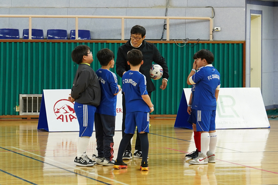 Cha Bum-kun, center, teaches young kids football at Paryeong Stadium in Goheung County, South Jeolla on Sunday. [FOOTWORK CREATION]