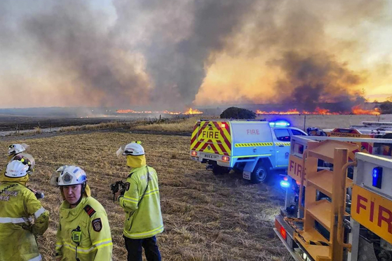 West Australian firefighters watch as grassland burns near the West Australian city of Wannaroo, north of Perth in the early hours of Thursday, Nov. 23, 2023. [Dept. of Fire and Emergency Services via AP]