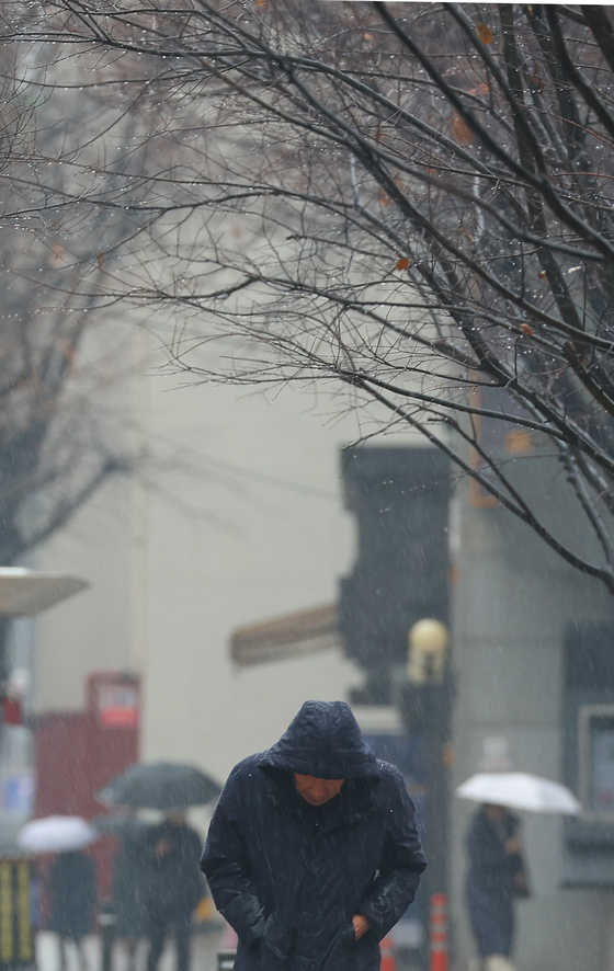 A man with his hood on walks in the rain on a street in Jongno District, central Seoul, on Wednesday at noon, a day before Daeseol, the season of heavy snow according to the lunar calendar. [YONHAP]