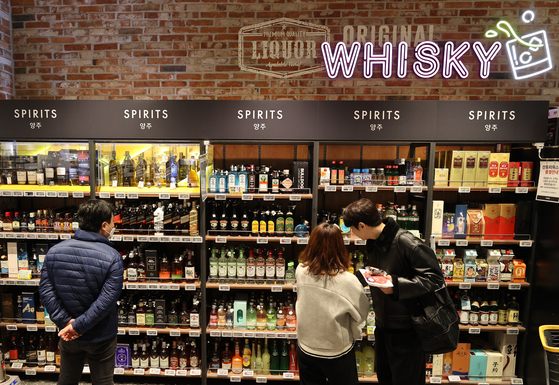 Customers browse whiskey products at a supermarket in downtown Seoul. [YONHAP]