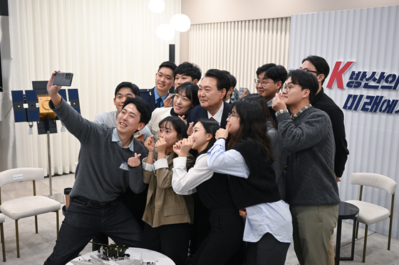 President Yoon Suk Yeol, center, takes a selfie with young professionals working in the defense industry during a visit to LIG Nex1 in Seongnam, Gyeonggi, on Thursday. [PRESIDENTIAL OFFICE]