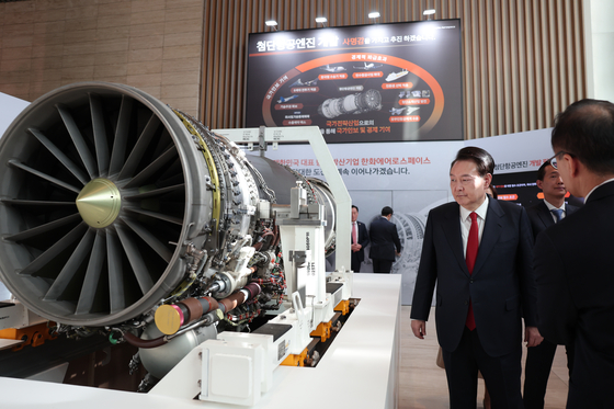 President Yoon Suk Yeol, left, views an aircraft engine after the second defense industry exports strategy meeting held at Hanwha Aerospace in Pangyo, Gyeonggi, on Thursday. [JOINT PRESS CORPS]
