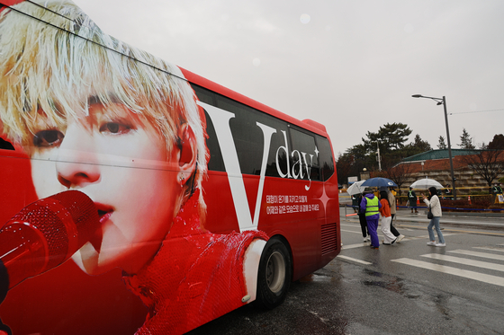 A red chartered bus featuring BTS V's face parked in front of the military boot camp in Nonsan, South Chuncheong on Monday, as members V and RM begin their mandatory military service. [YONHAP] 