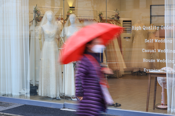A woman passes by a wedding dress shop in Ahyeon-dong in Mapo District, western Seoul, on Monday. [YONHAP]