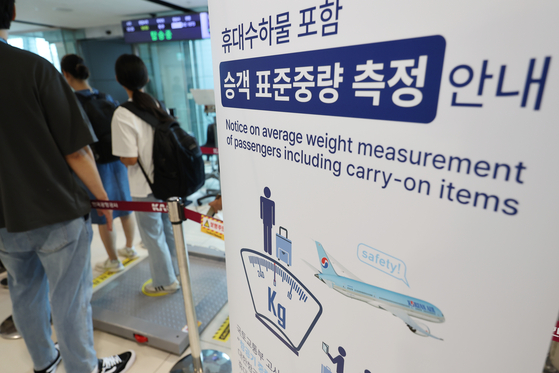 A Korean Air sign informs its passengers of measuring their body weights, including their carry-on items, as part of data collection to calculate the average weight of passengers on flights at a departure gate for a domestic flight at Gimpo International Airport in Gangseo District, western Seoul, on Aug. 28. [NEWS1]
