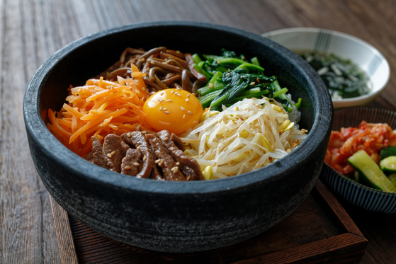 Traditional bibimbap topped with a variety of sauteed and seasoned vegetables and an egg yolk, served in a hot stone pot [SHUTTERSTOCK]