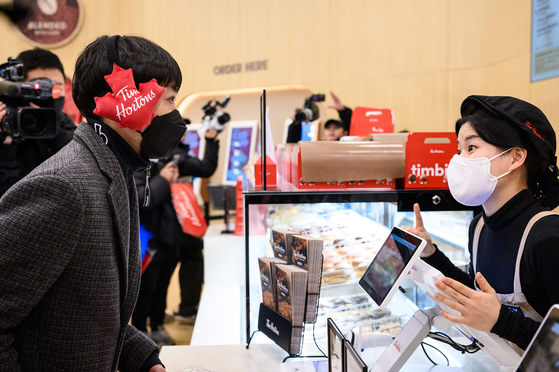 Thirty-nine-year-old Shim Jae-ho, left, became Tim Hortons Korea's first customer, placing an order at the inaugural store on Thursday. Shim had waited for 23 hours, starting from 11 a.m. the day before, to secure the coveted position of being the first customer. [TIM HORTONS KOREA]