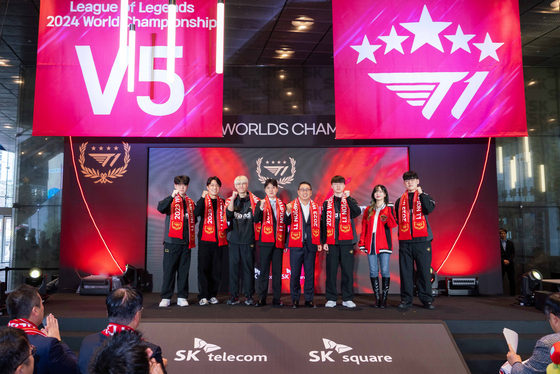 Korea Esport team T1 members including Lee “Faker” Sang-hyeok, third from right, and SK Telecom CEO Ryu Young-sang, fourth from right, pose for a photo during a ceremony celebrating T1's victory at this year’s League of Legends World Championship held at SK Telecom's headquarters in central Seoul on Monday. [SK TELECOM]