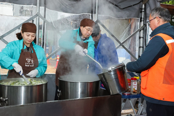 Volunteers including Hana Bank executives and employees, alongside members of the Myeong-dong Merchants Association, help out at the Myeong-dong Bab House, a soup kitchen located in Myeongdong, central Seoul. [HANA BANK]